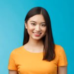 Close-up charming attractive asian girl pure clean skin condition, smiling joyfully look camera upbeat, politely listen, express positive good mood motivated achieve success, stand blue background.