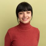 pleased young brunette caucasian girl looks at camera isolated on olive green background with copy space